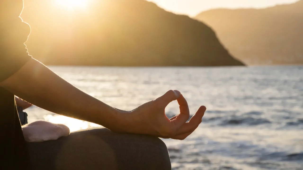 woman meditating by the sea at sunset