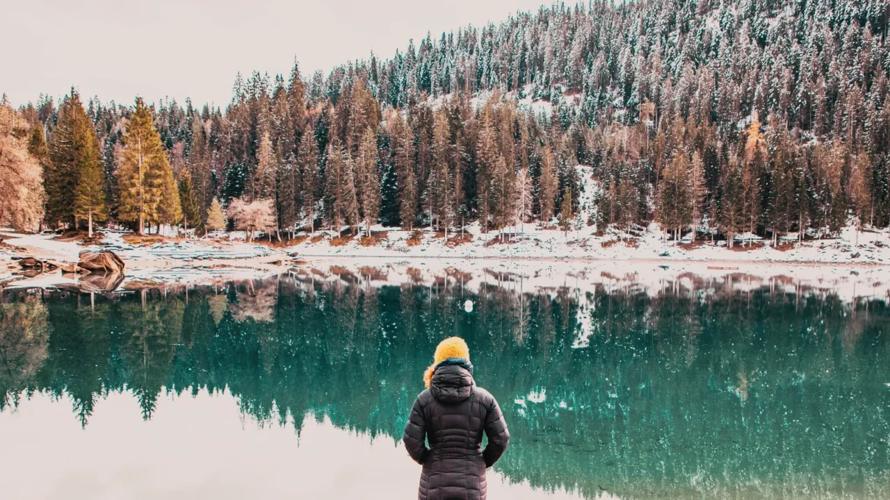 woman watchin amazing turquoise water of caumasee in winter switzerland