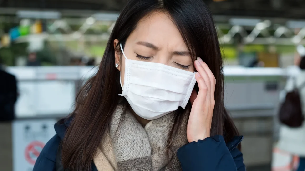 woman with face mask feeling headache