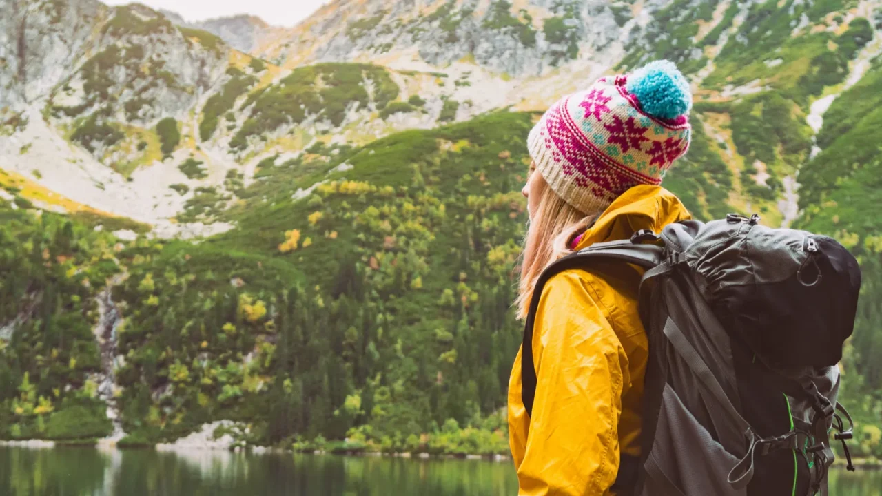 young blond hair woman with big camping rucksack wearing yellow