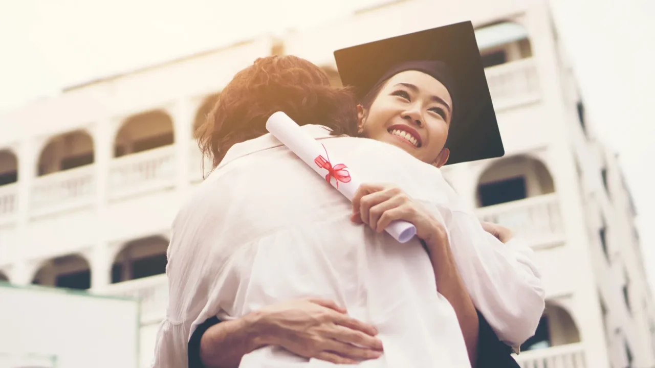 young female graduate hugging her mother at graduation ceremony successgoal