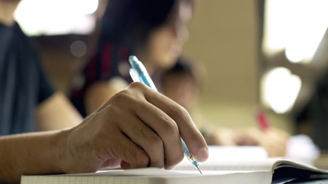 young man doing homework and studying in college library