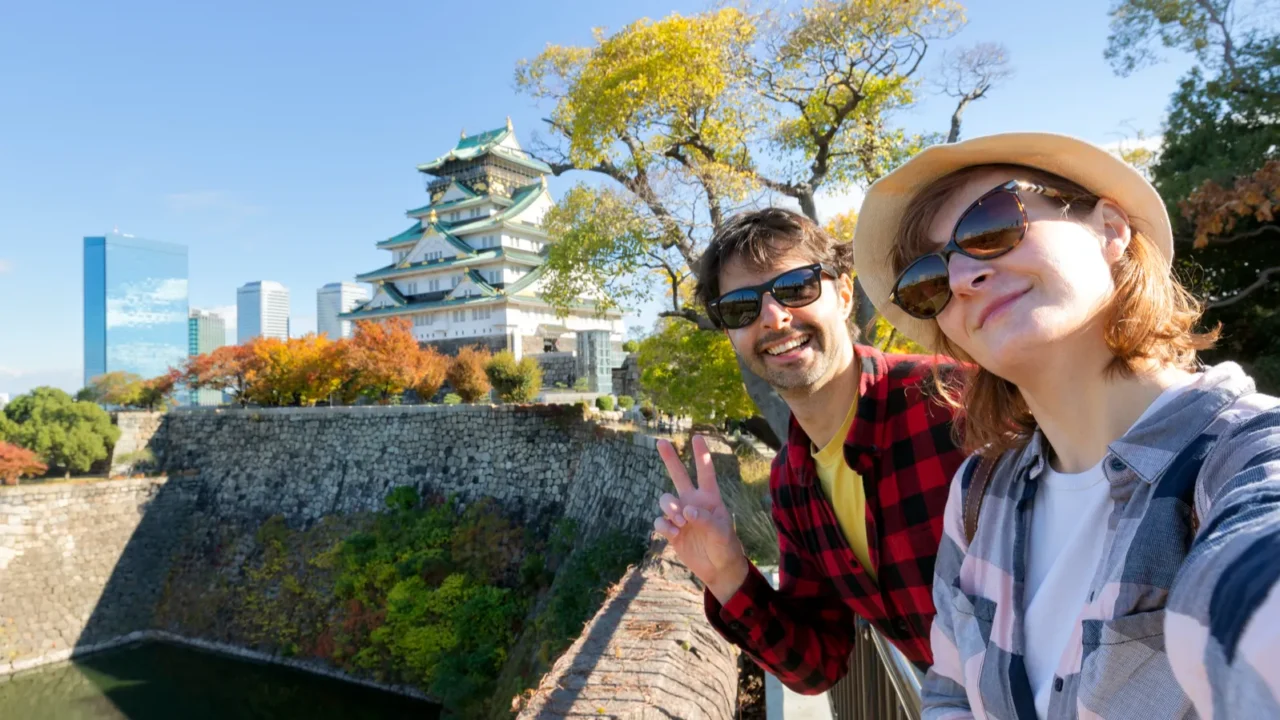 a young travel couple takes a selfie at osaka castle