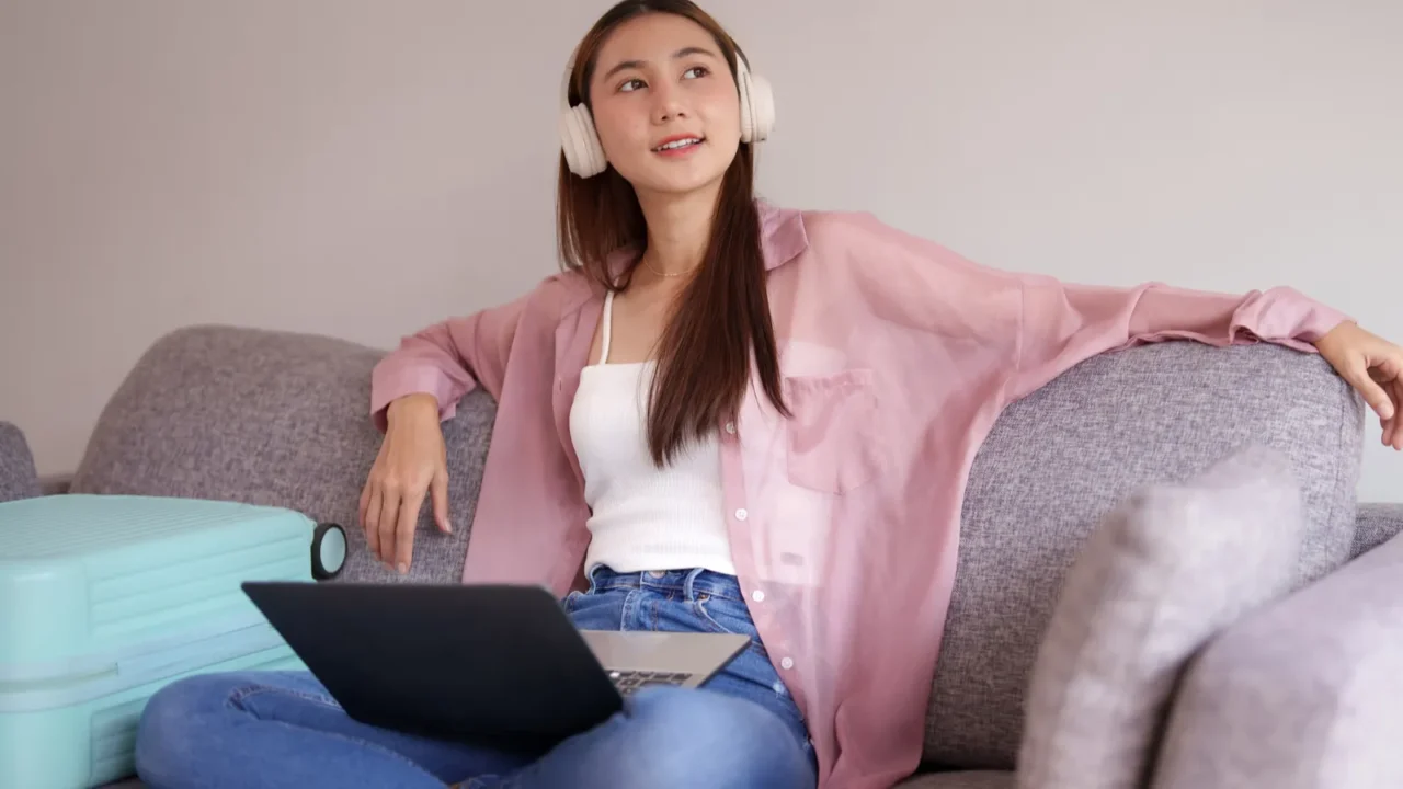 adult asian woman plans vacation online from comfortable living space