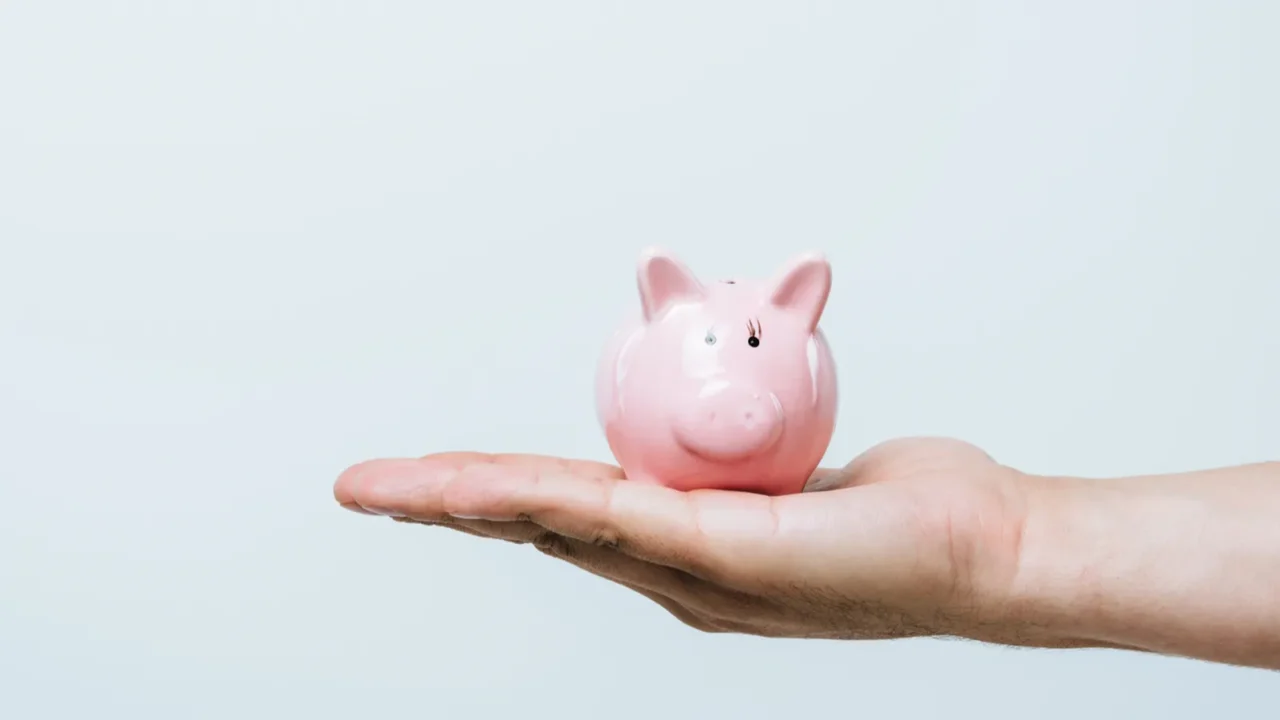 cropped image of man holding pink piggybank isolated on grey