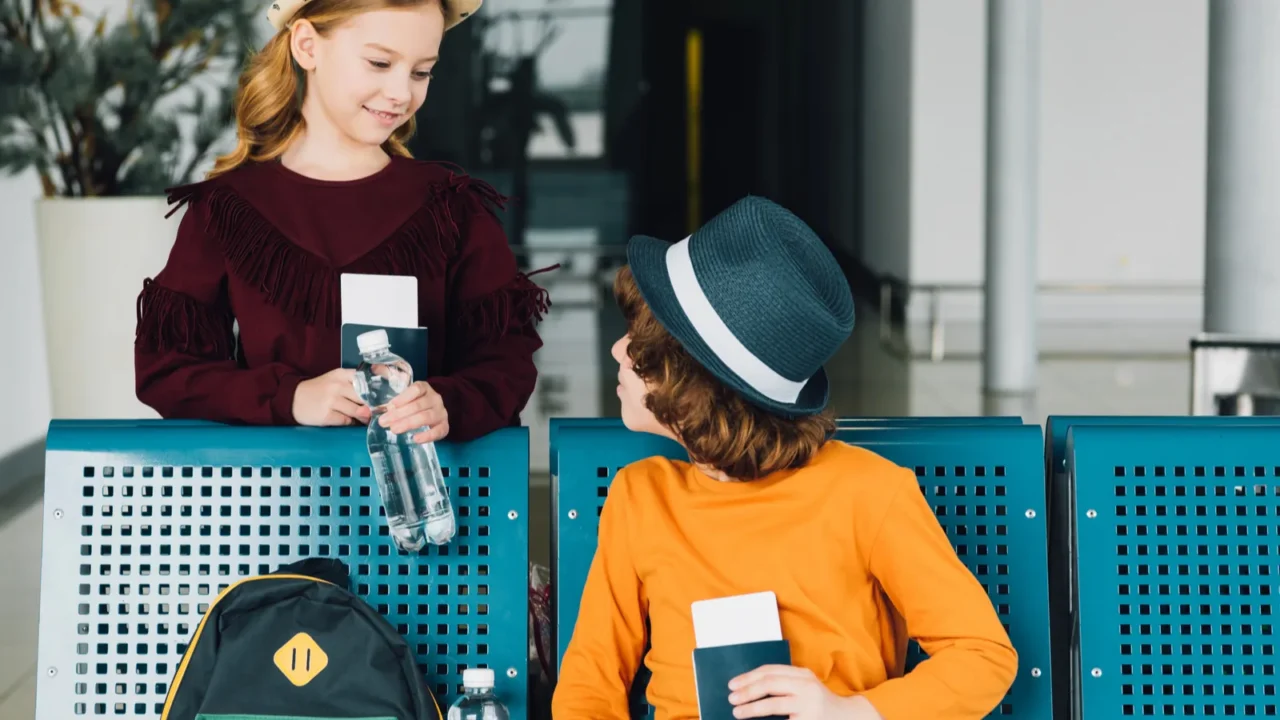 cute preteen kids in waiting hall with air tickets and