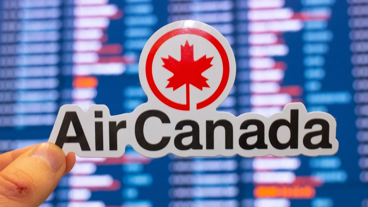 The emblem of the Air Canada airline against the background of an electronic board with a flight schedule at an international airport.