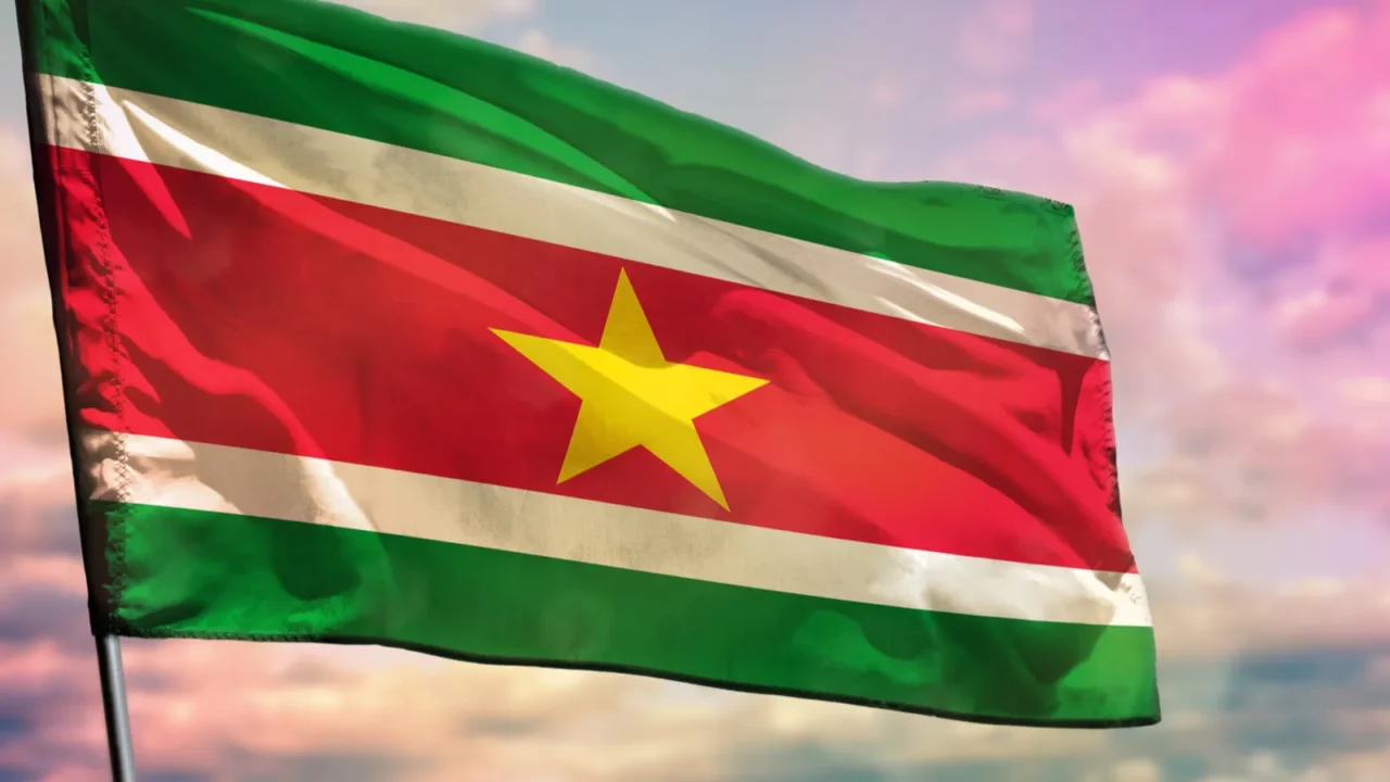 fluttering suriname flag on colorful cloudy sky background prosperity concept