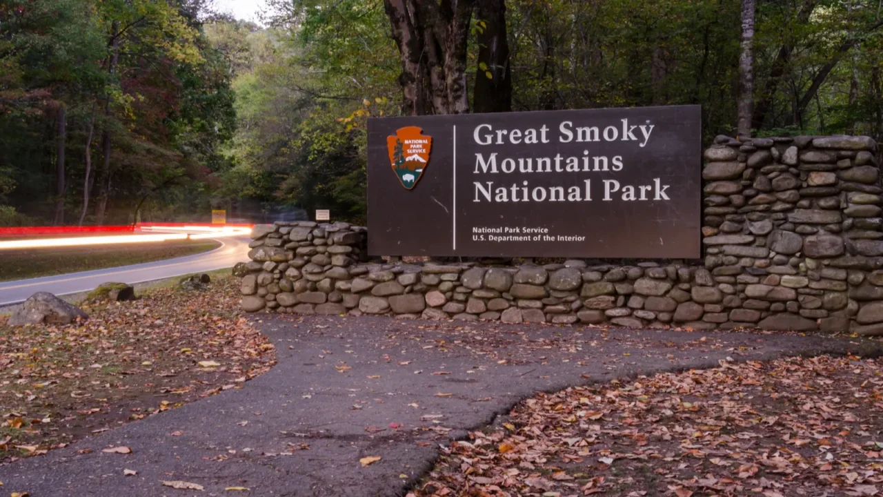 great smoky mountains entry sign with car lights
