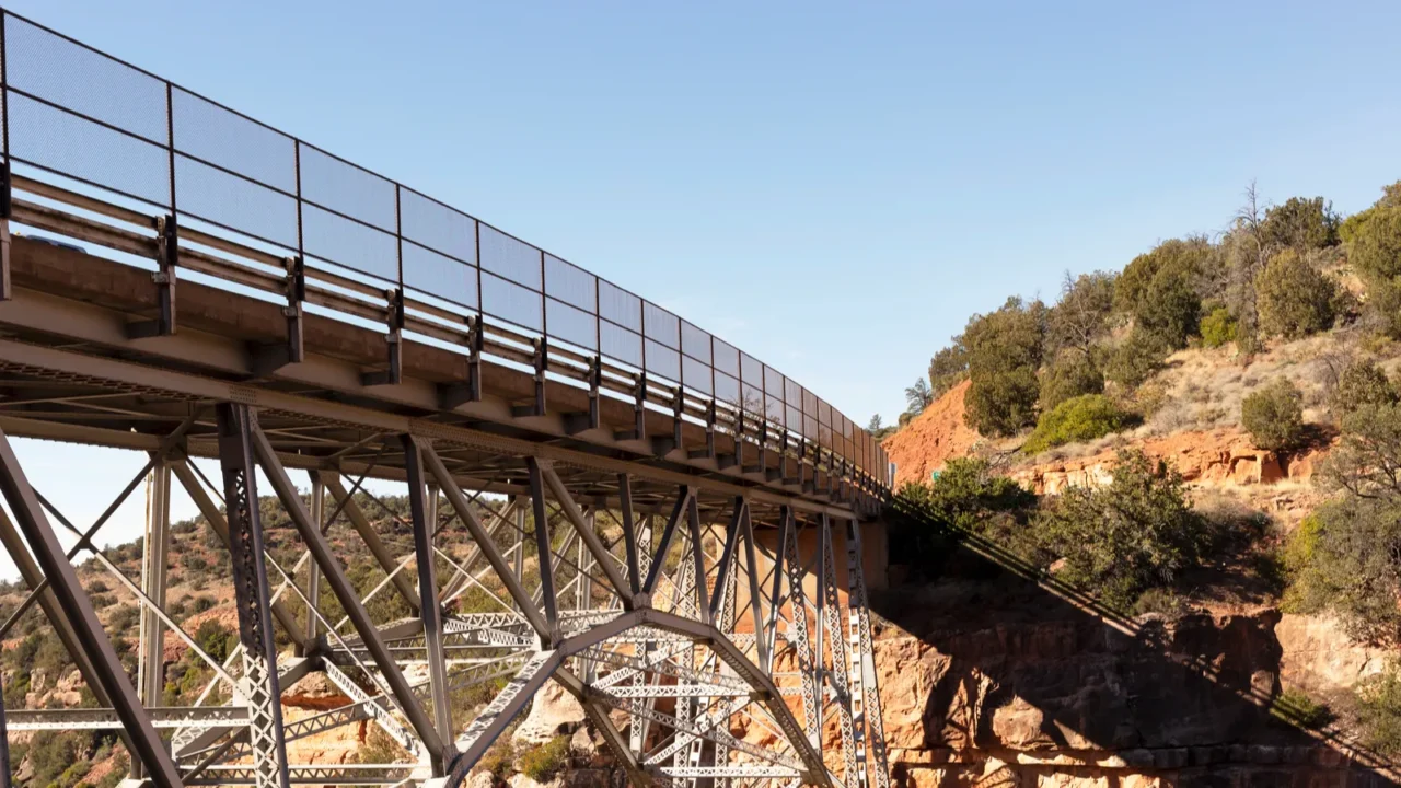 metal construction of bridge supports against blue sky and rocks
