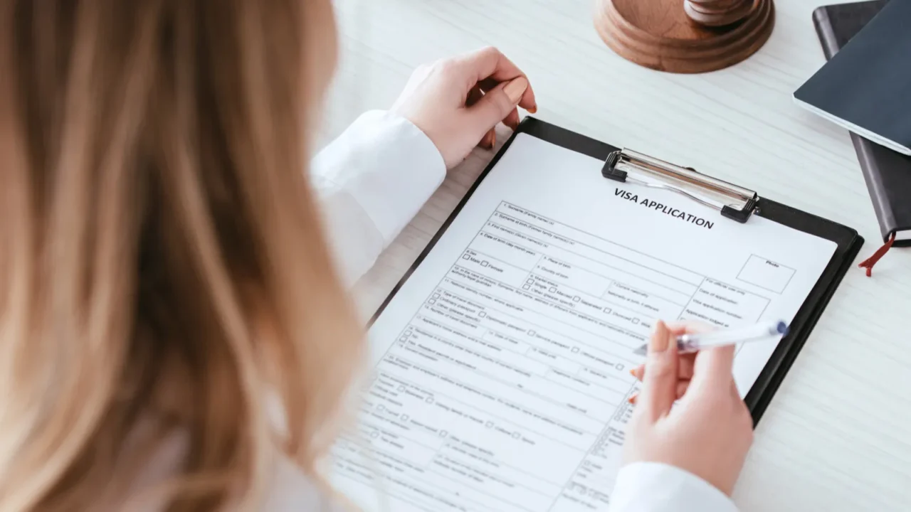 selective focus of woman holding pen near document with visa
