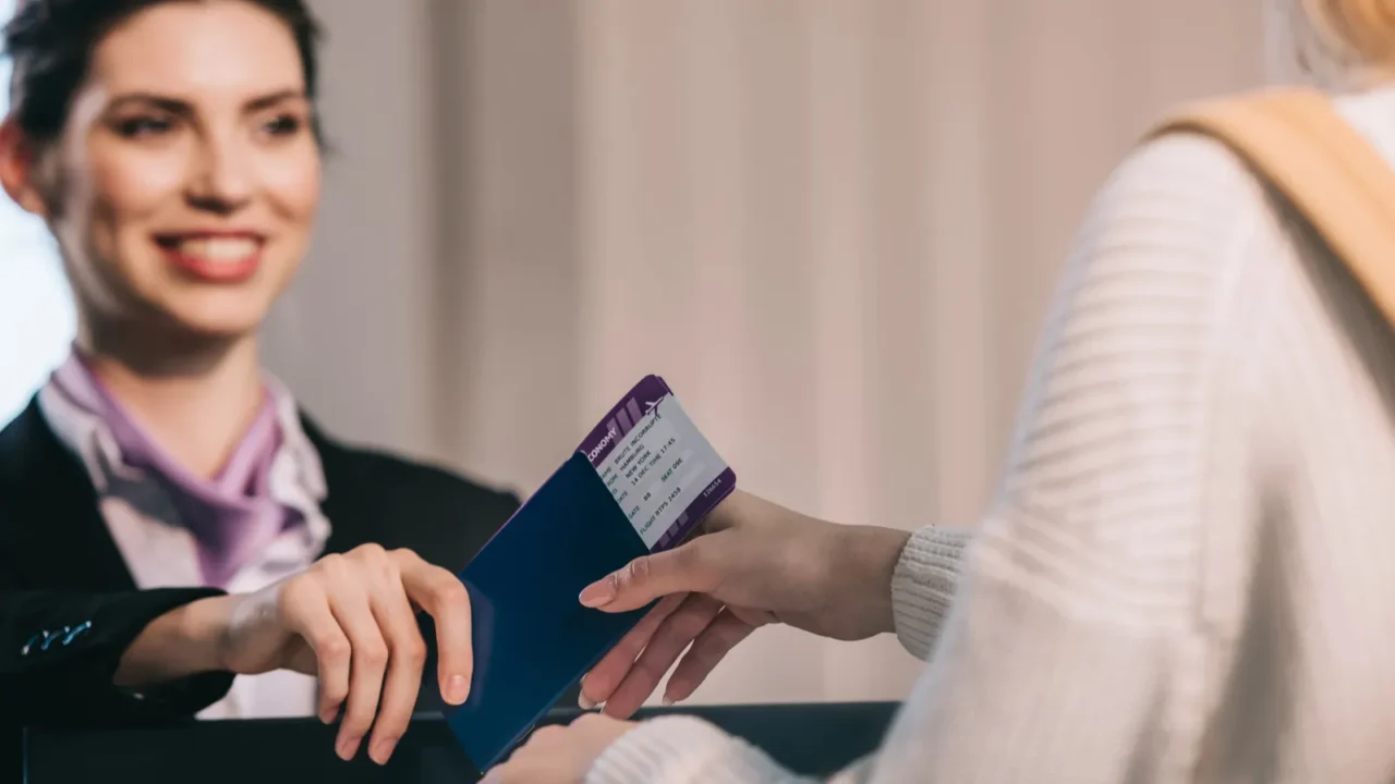 smiling airport worker giving passport with boarding pass to young
