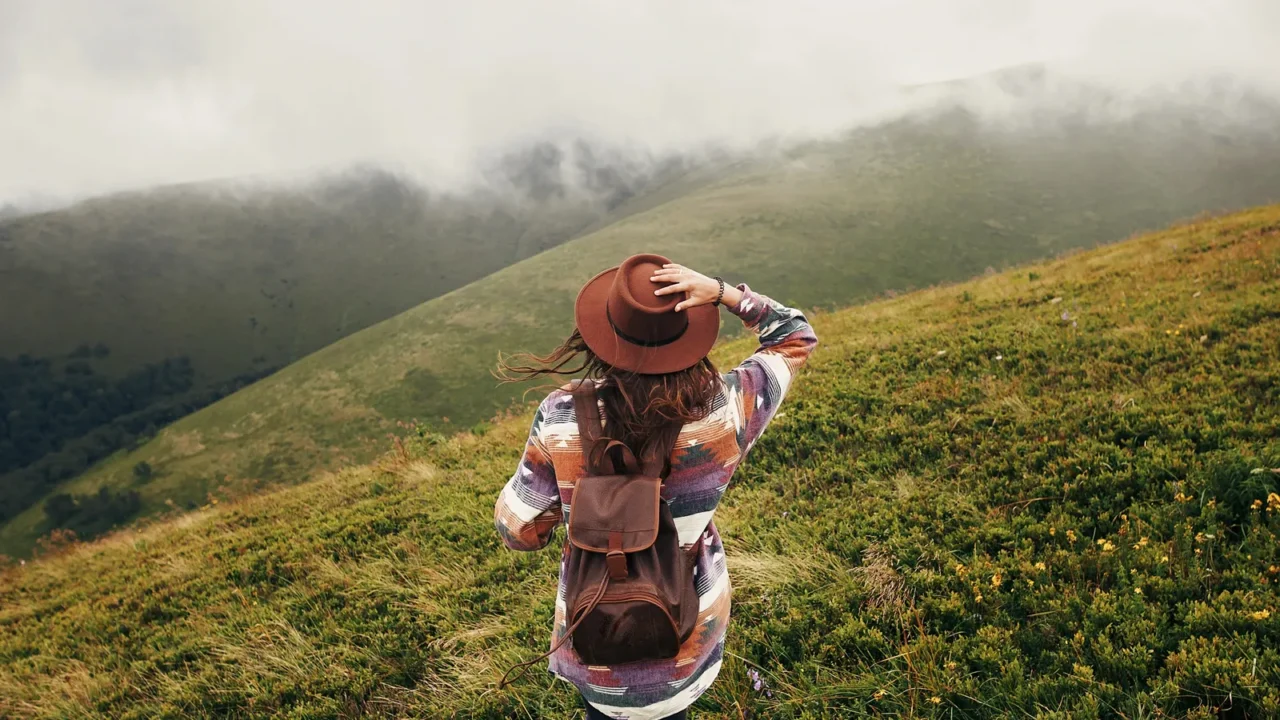 stylish traveler girl in hat with backpack looking at sunny