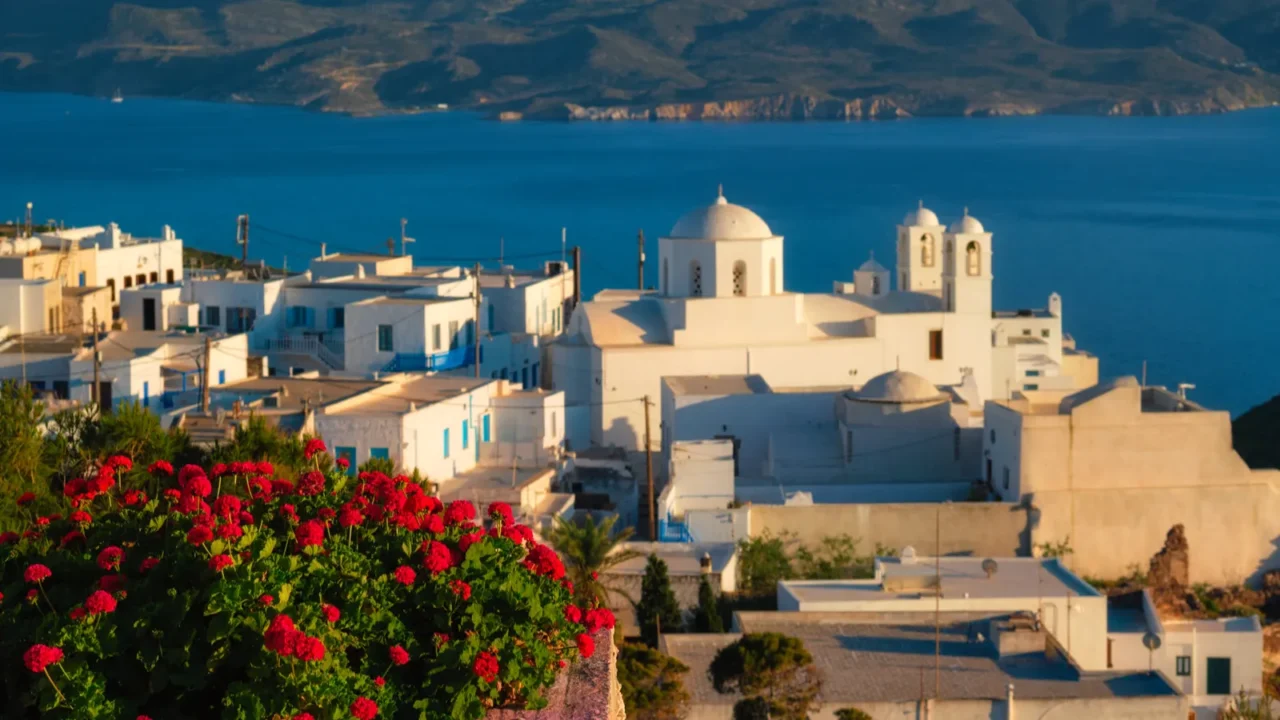 view of plaka village on milos island over red geranium