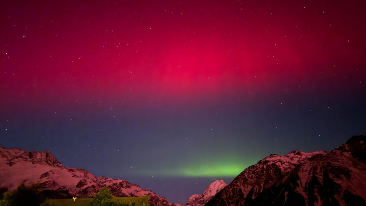 Amazing miraculous beautiful red grey green colour of Aurora Australis at night during dark starry sky in the southern island of New Zealand with Mount Cook background in fall season
