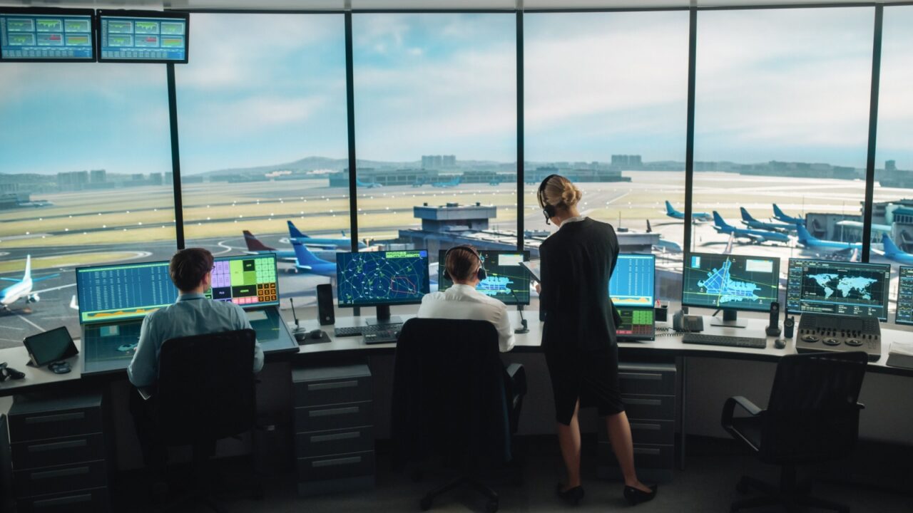 Diverse Air Traffic Control Team Working in a Modern Airport Tower. Office Room is Full of Desktop Computer Displays with Navigation Screens, Airplane Departure and Arrival Data for Controllers.