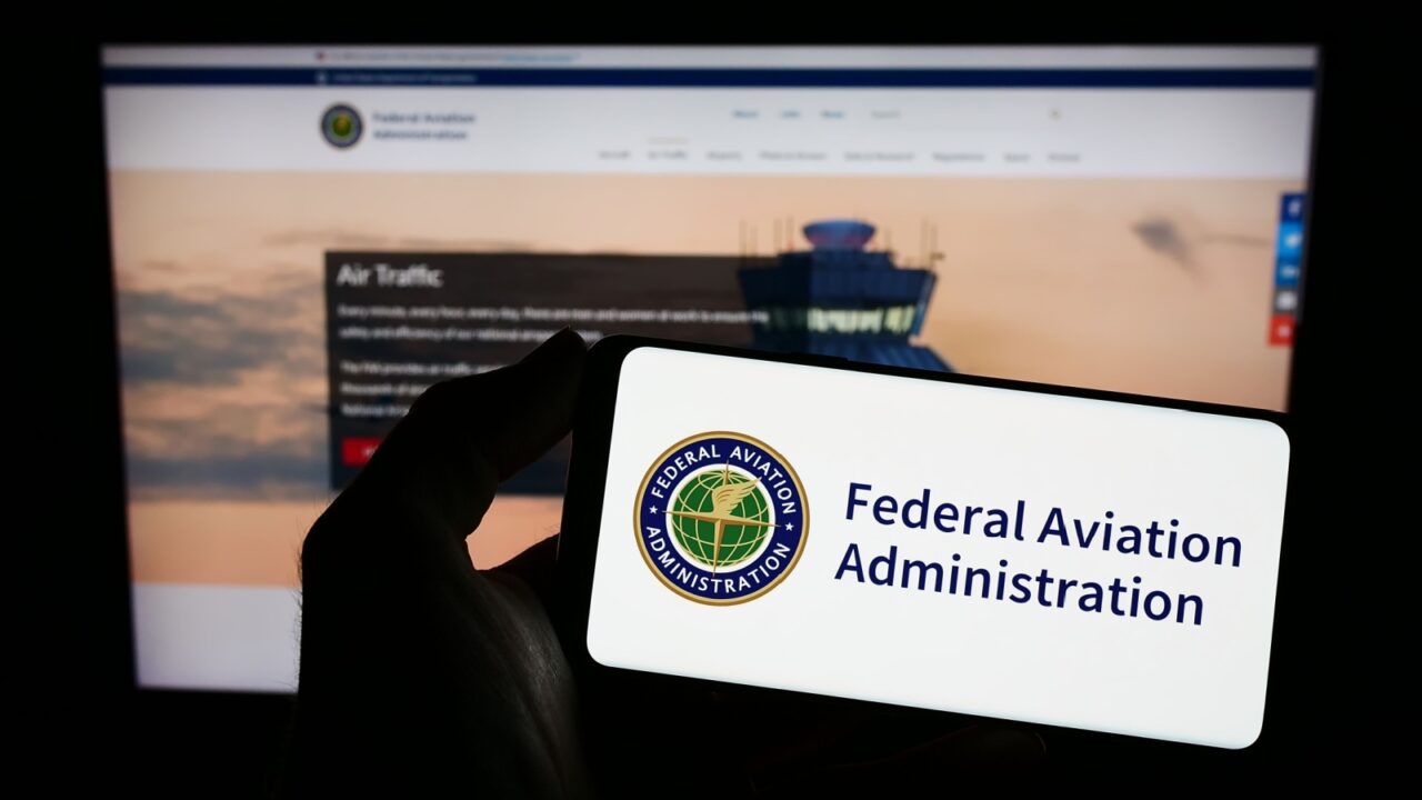Stuttgart, Germany - 01-24-2023: Person holding mobile phone with seal of American Federal Aviation Administration (FAA) on screen in front of web page. Focus on phone display. Unmodified photo.
