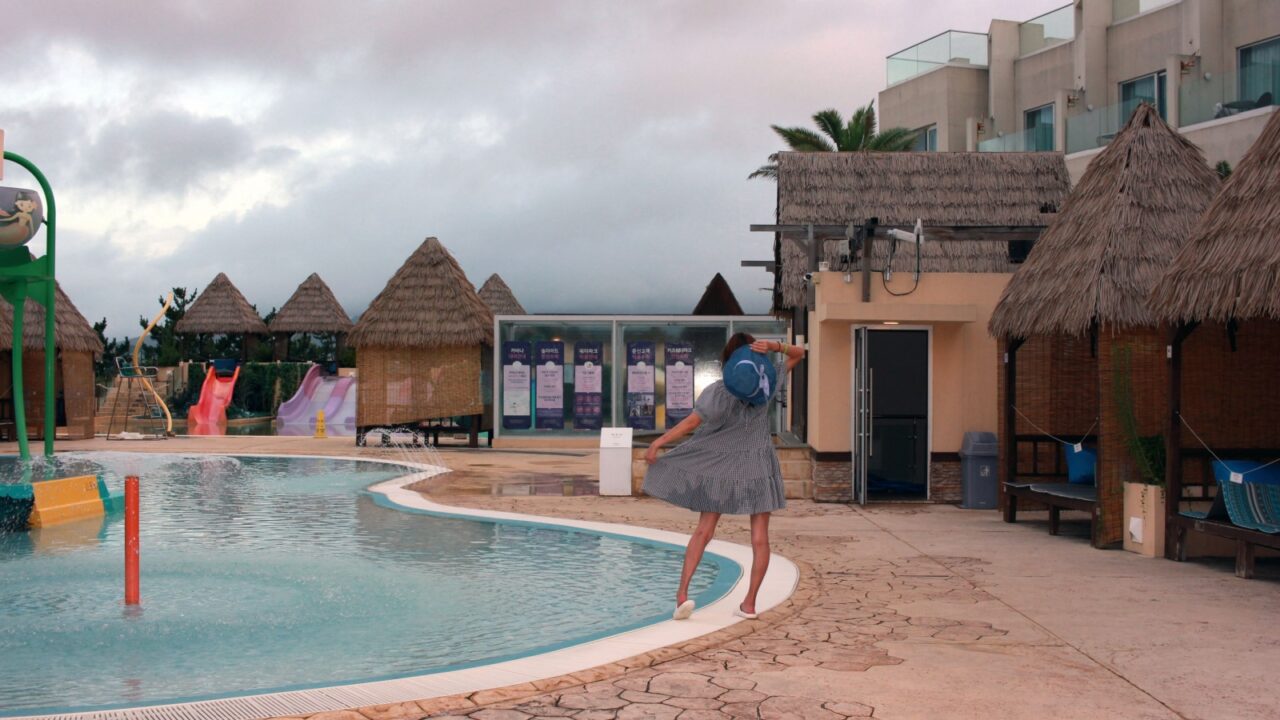 Dolsan-eup, Yeosu-si, South Korea - July 26, 2024: Young woman watching sunrise at a resort with a swimming pool overlooking the sea in Yeosu