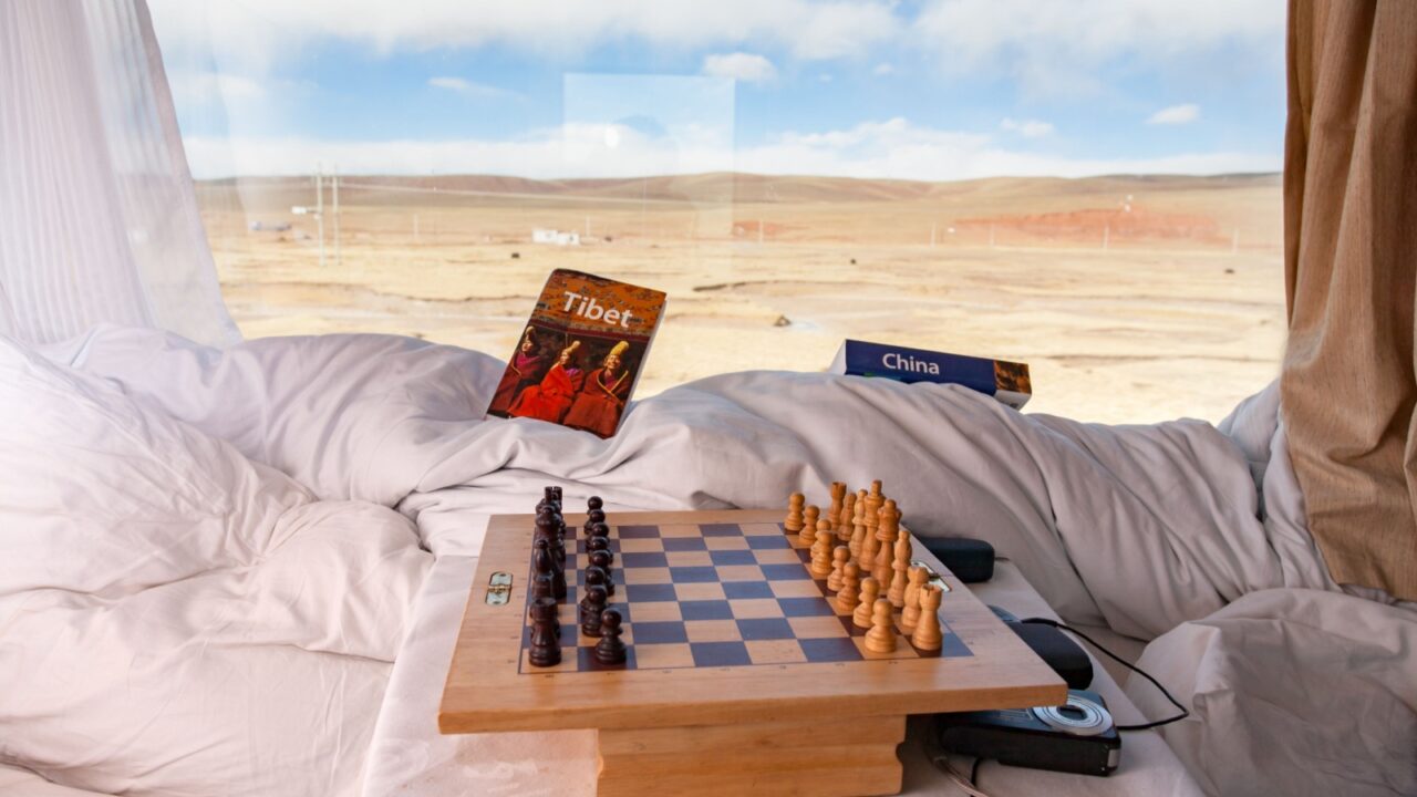 NAGCHU (NAQU), TIBET, CHINA, DECEMBER 28, 2006: inside comfortable soft sleeper in train from Beijing to Lhasa, Tibet Express, chess game, camera and travel guide book in front of window