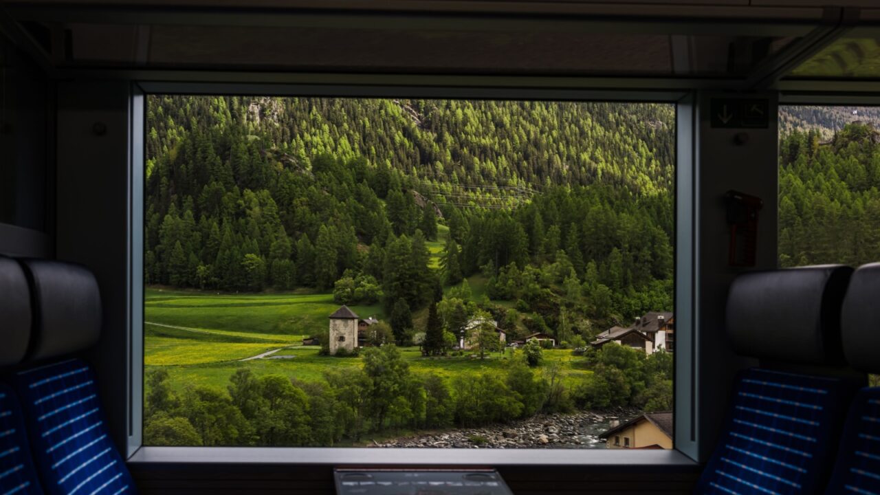 Framed view from a train window of a quiet alpine valley