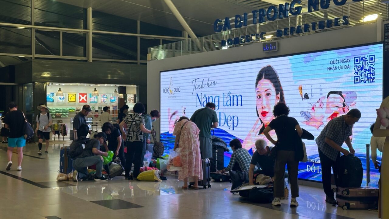 t Phu Quoc Airport, Vietnam – March 01, 2025: Passengers rearrange luggage to meet airline weight limits. Some sit on the floor while adjusting their bags.
