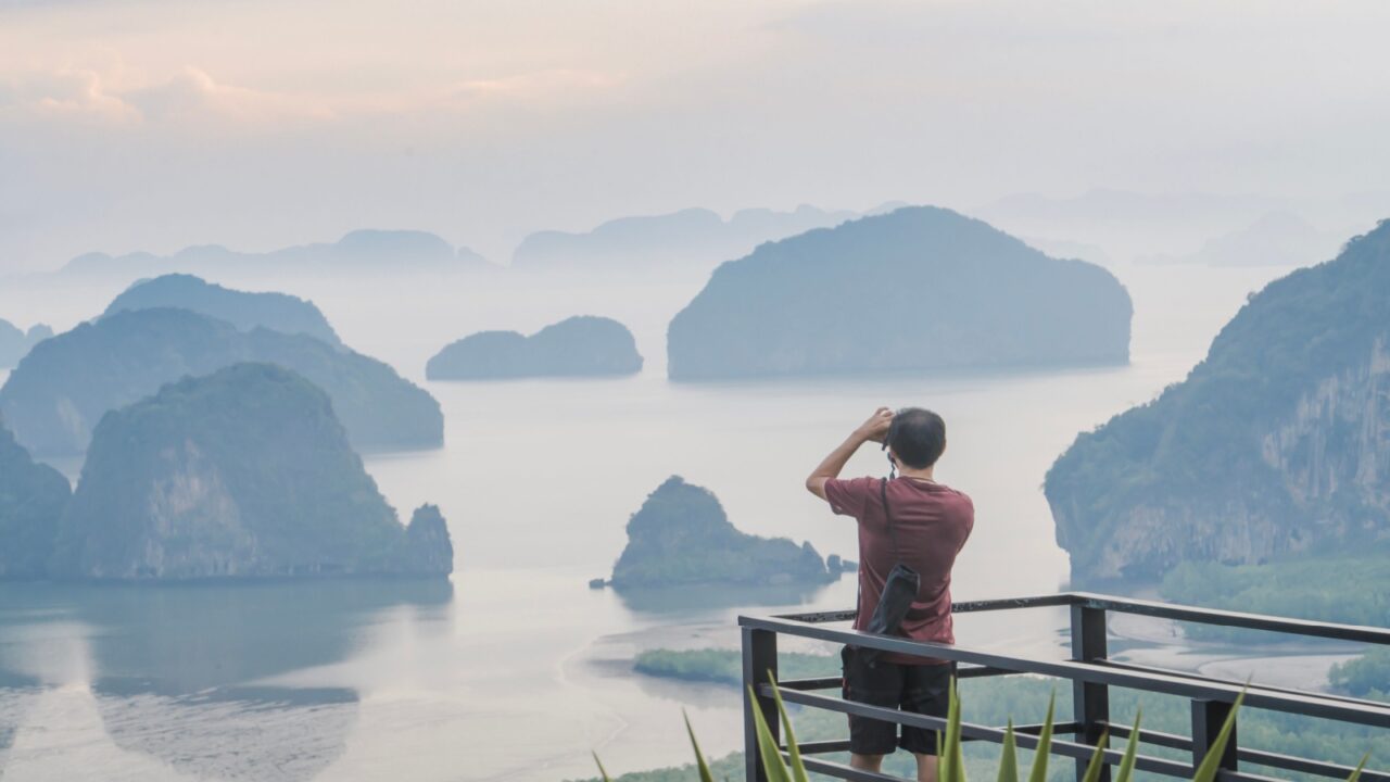A photographer photographs a beautiful view from the Samet Nanghse observation deck in Thailand.Morning view of the blue mountains and stones in the water in Thailand, mysterious beauty. Tourism