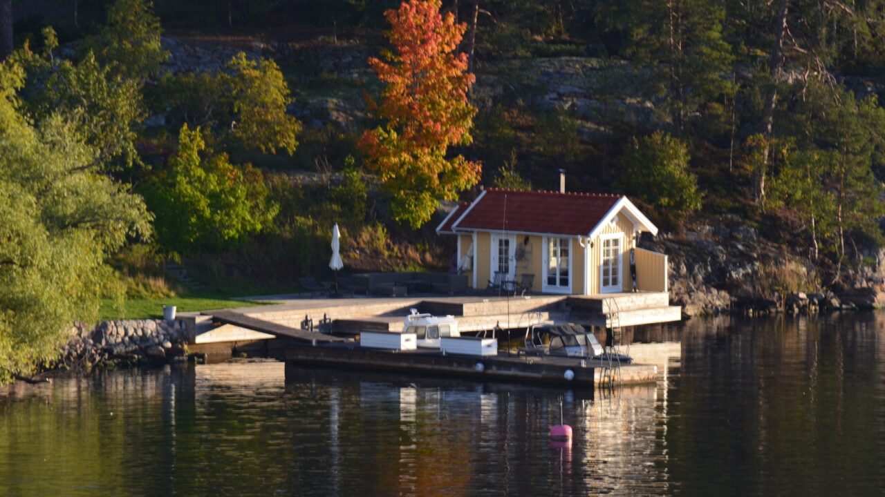 Stockholm, Sweden - 10.07.2025: Small Swedish lakeside cabin surrounded by autumn forest near calm water
