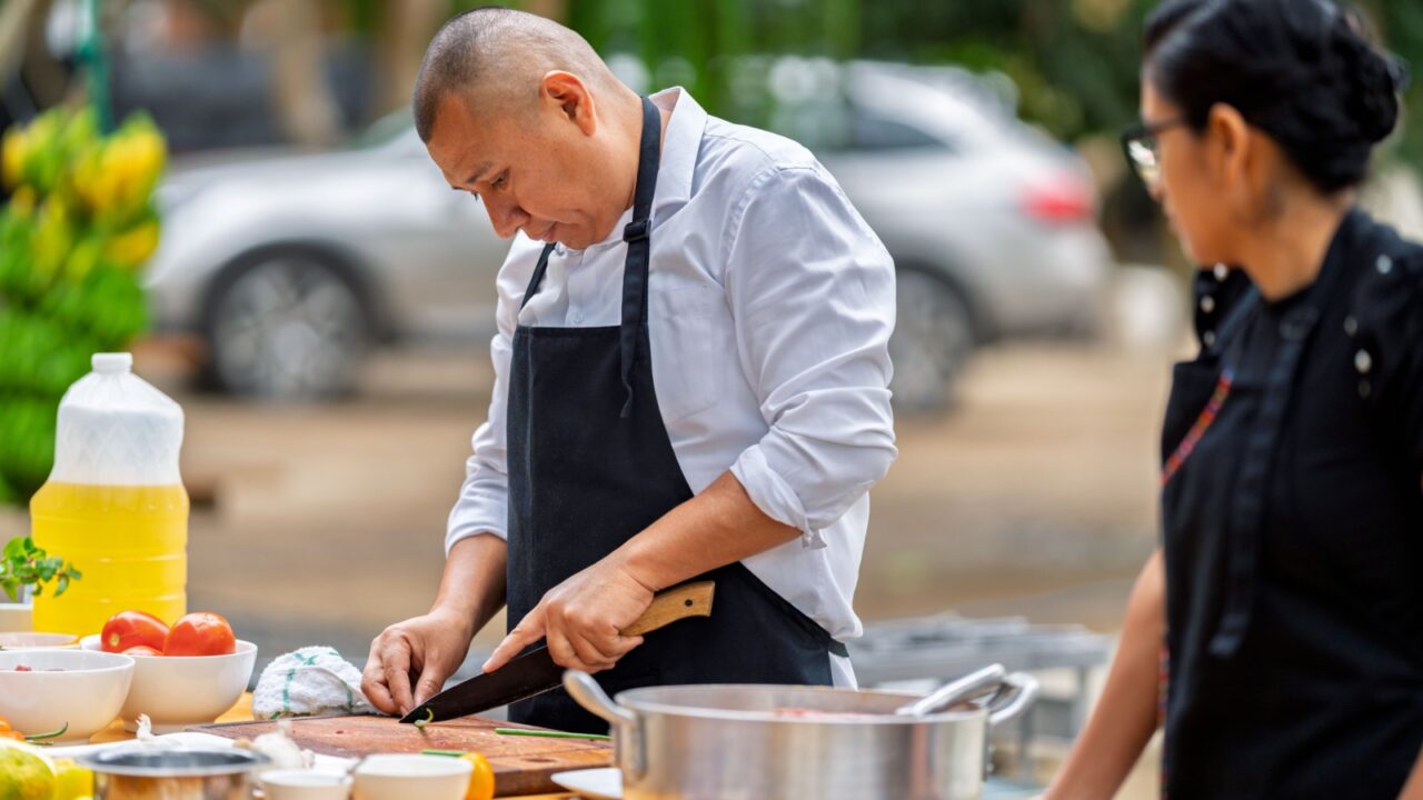 Chef cutting fresh vegetables outdoors, focusing on culinary preparation with healthy ingredients for a country restaurant