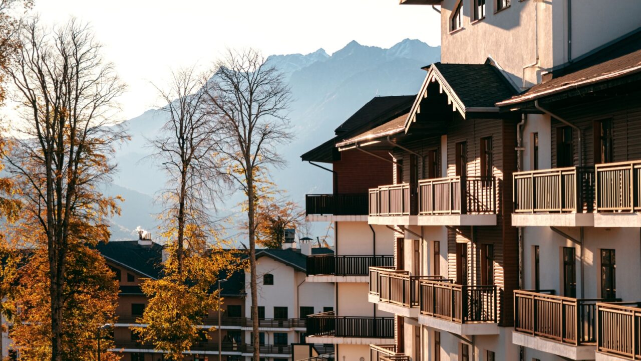, Sochi 10.13.2019 Roza Khutor. Beautiful houses with balconies on a background of yellow autumn trees, blue sky and mountains