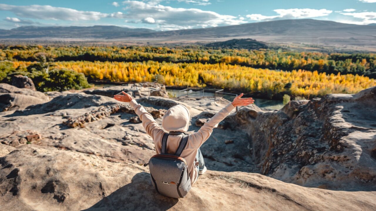 Happy tourist woman open arms and enjoying life and freedom on top of mountain in spring or autumn
