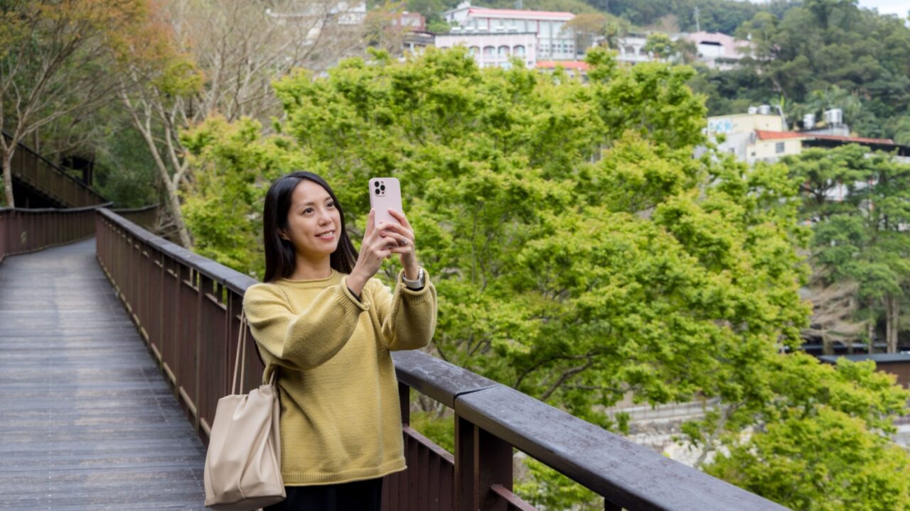 Tourist woman use mobile phone to take photo in the walking trail in the forest