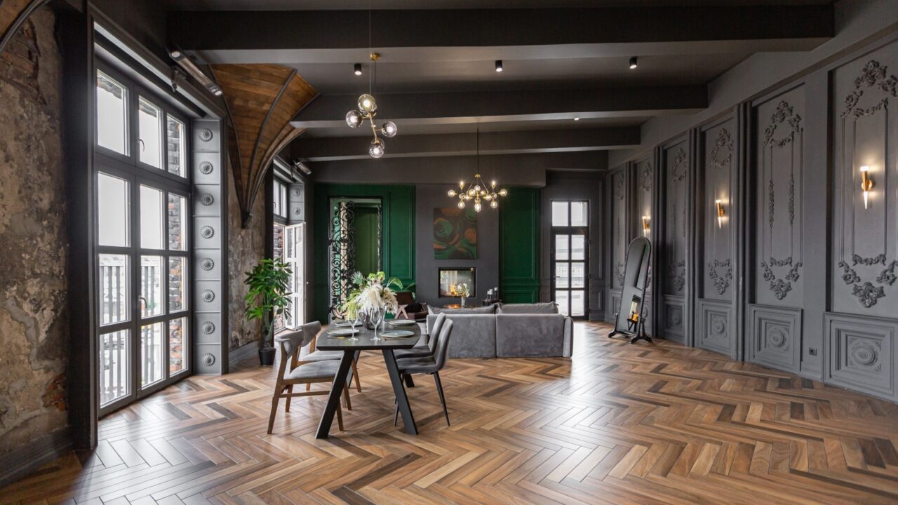 the dark brutal interior of the living room in a historical style in a mansion with panoramic windows. grey-green walls, brown parquet and modern furniture.