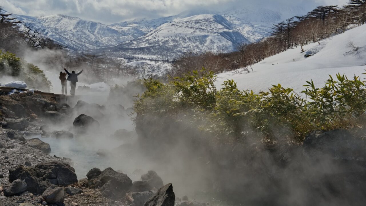 Tourists admire the steam of the picturesque thermal spring (Boiling River) near the Baranovsky volcano, the water temperature in the source of which is 80 degrees.