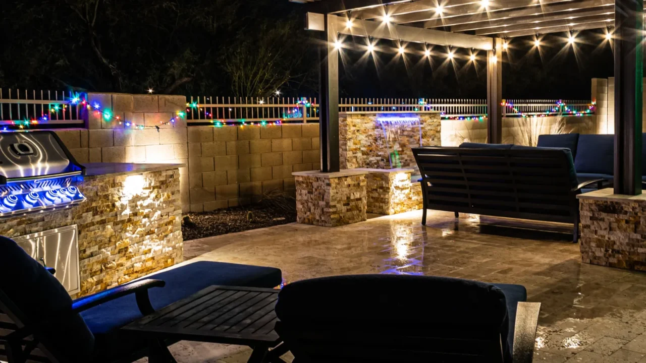 a resort style backyard at night with a waterfall pergola