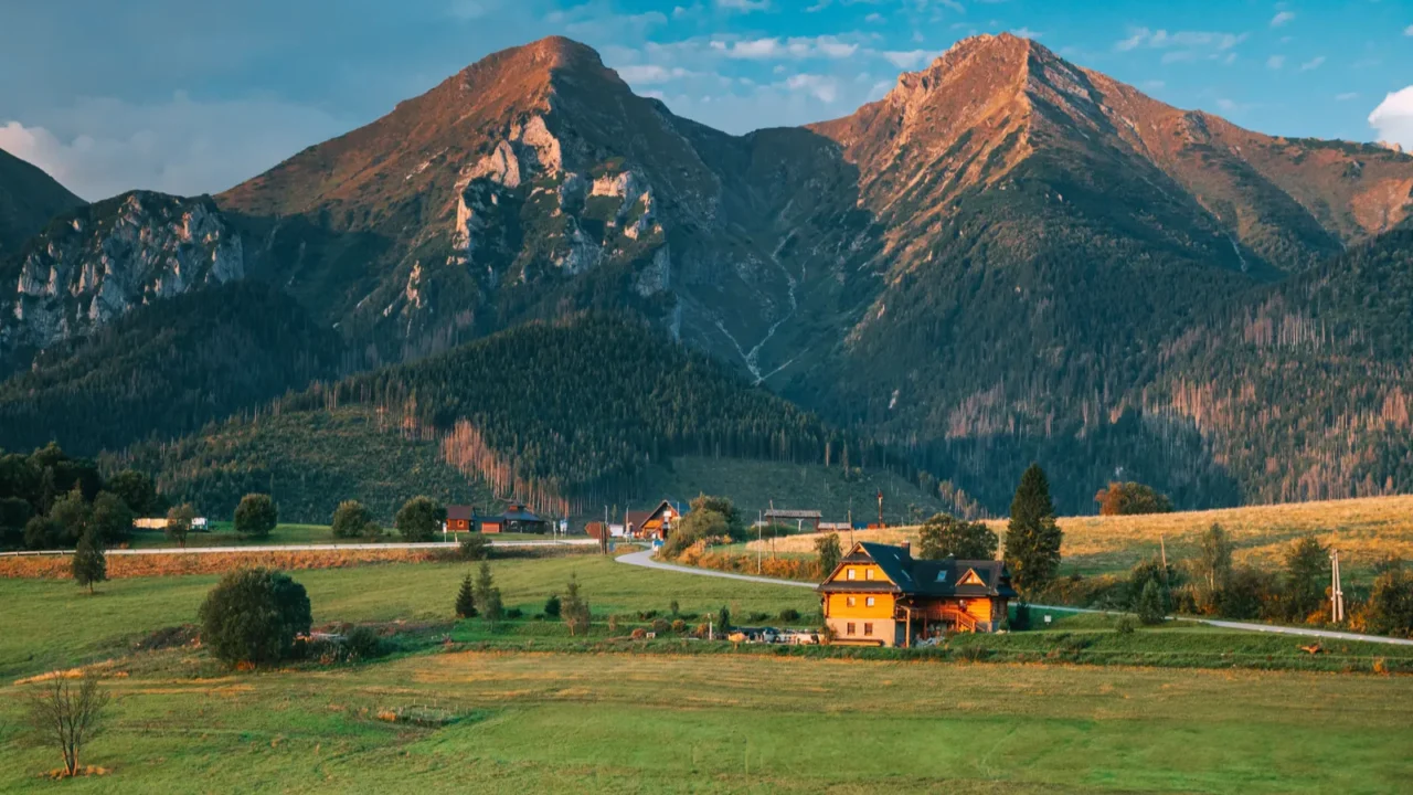 a wooden cabin under high mountains in morning light zdiar