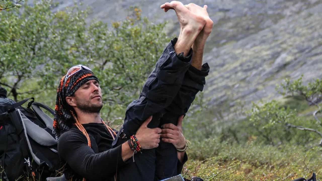 a young male tourist crouches to rest and stretches his