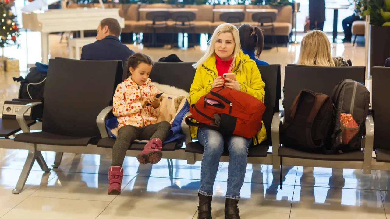 adorable toddler girl and her mom waiting at the airport