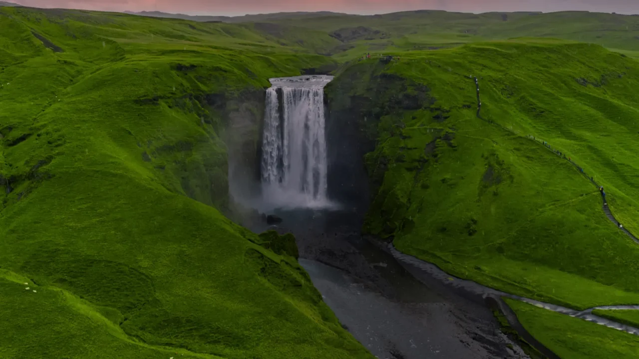 aerial view shows skogafoss plunging in a wide curtain into