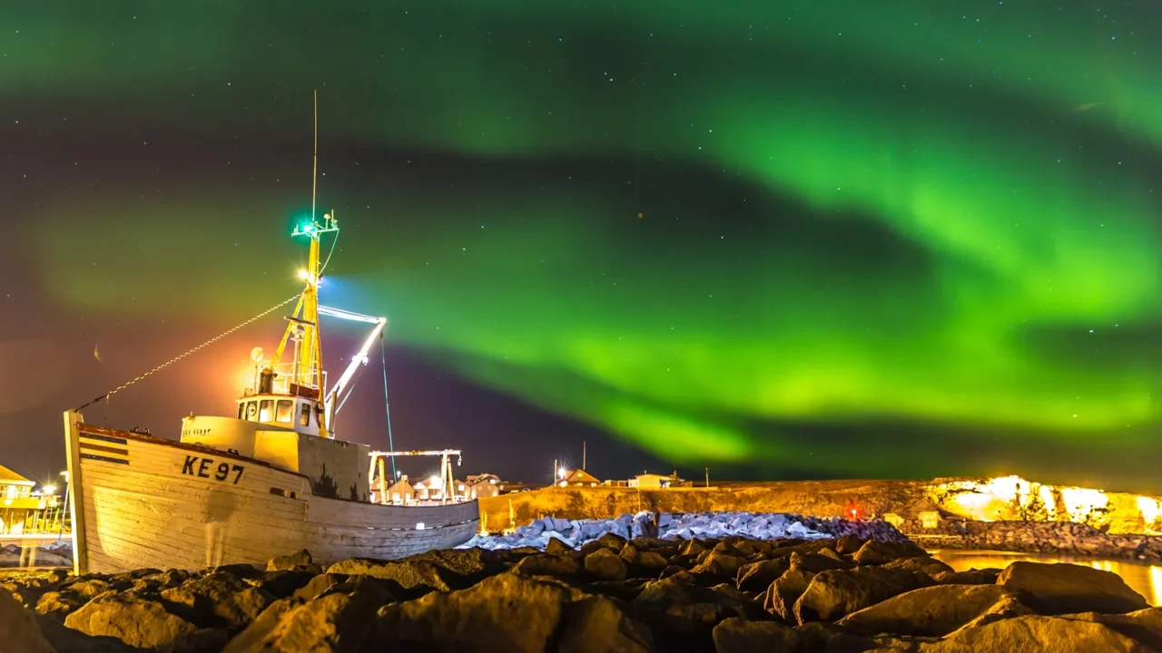 amazing northern lights at iceland boat and rocks in the