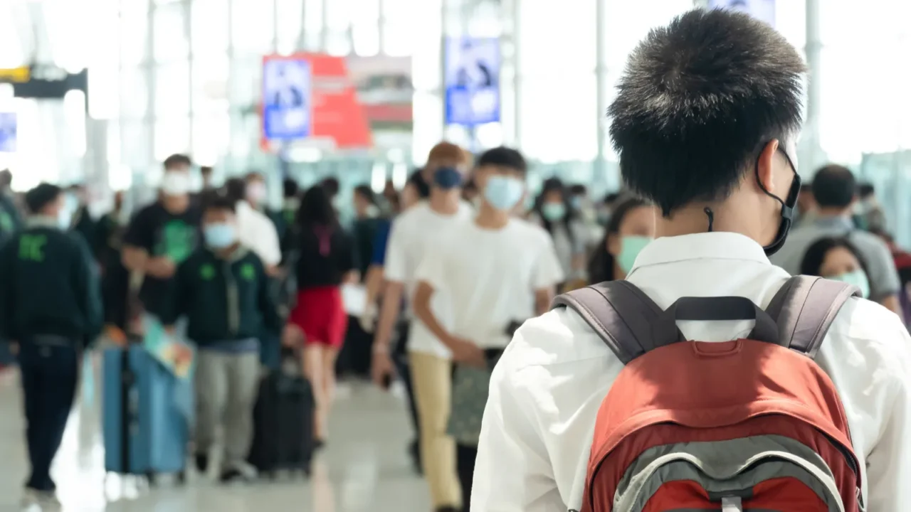 asian traveler man wearing face mask waiting to board into