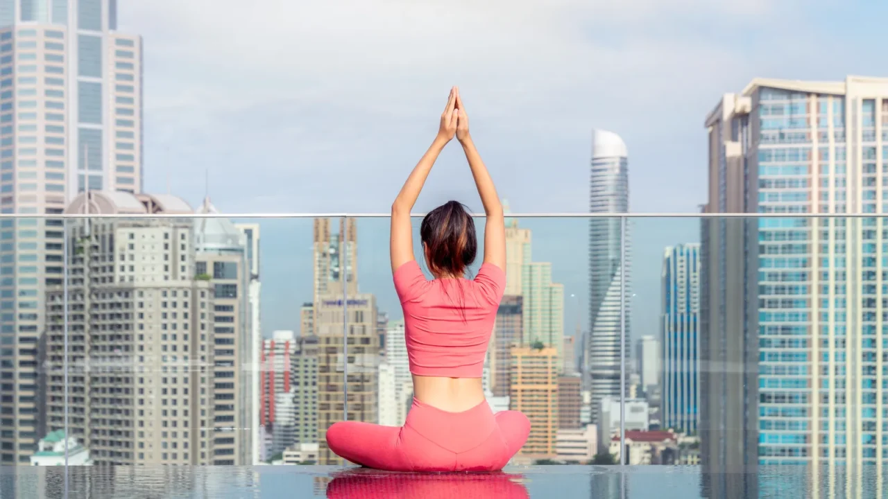 asian woman pose yoga action on hotel rooftop with bangkok