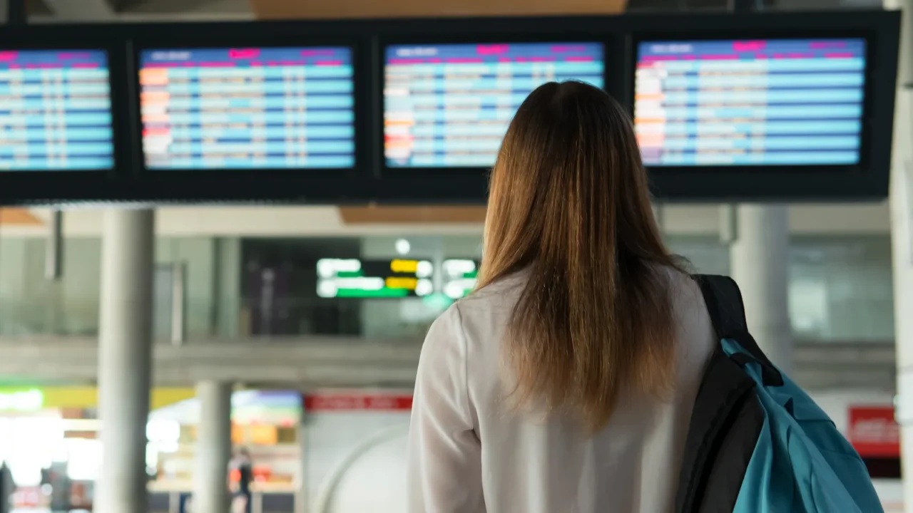 beautiful girl with backpack stands and choice flight