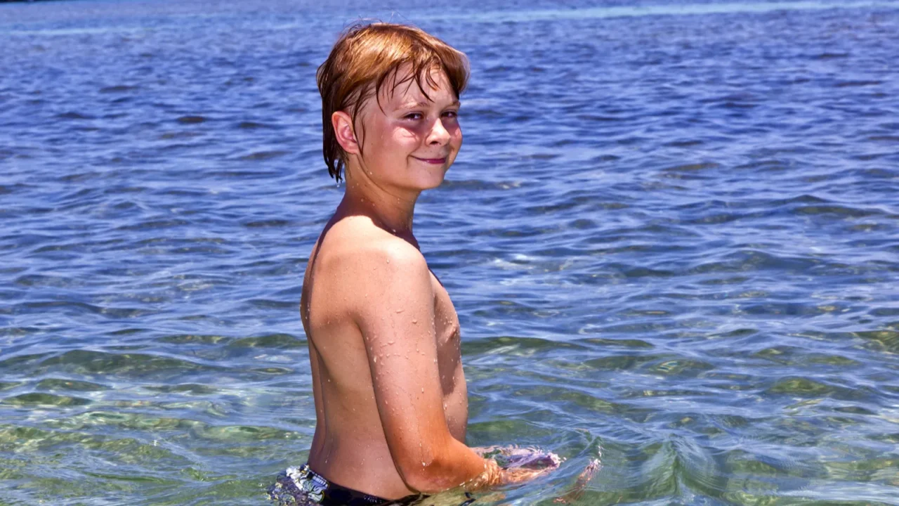 boy in the ocean swims in beautiful clear water