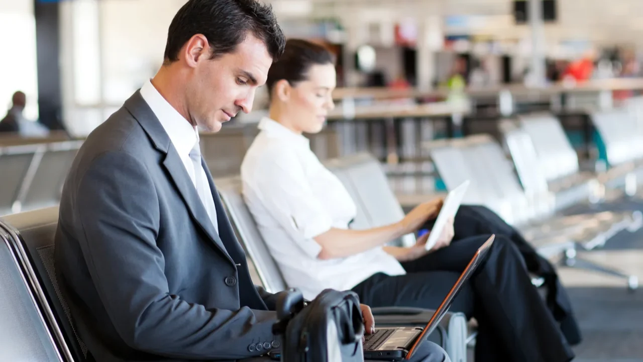 businessman and businesswoman using computer at airport
