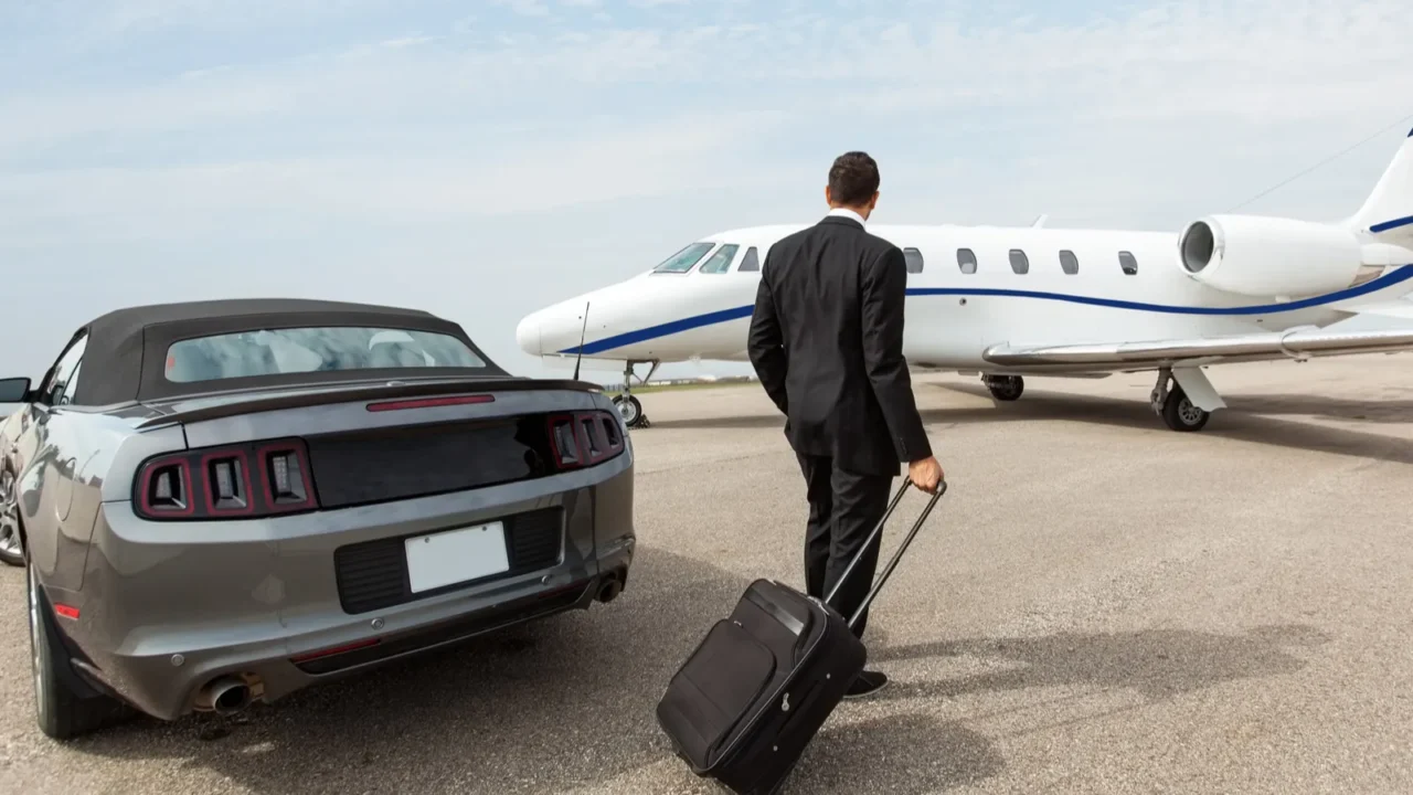 businessman standing by car and private jet at terminal