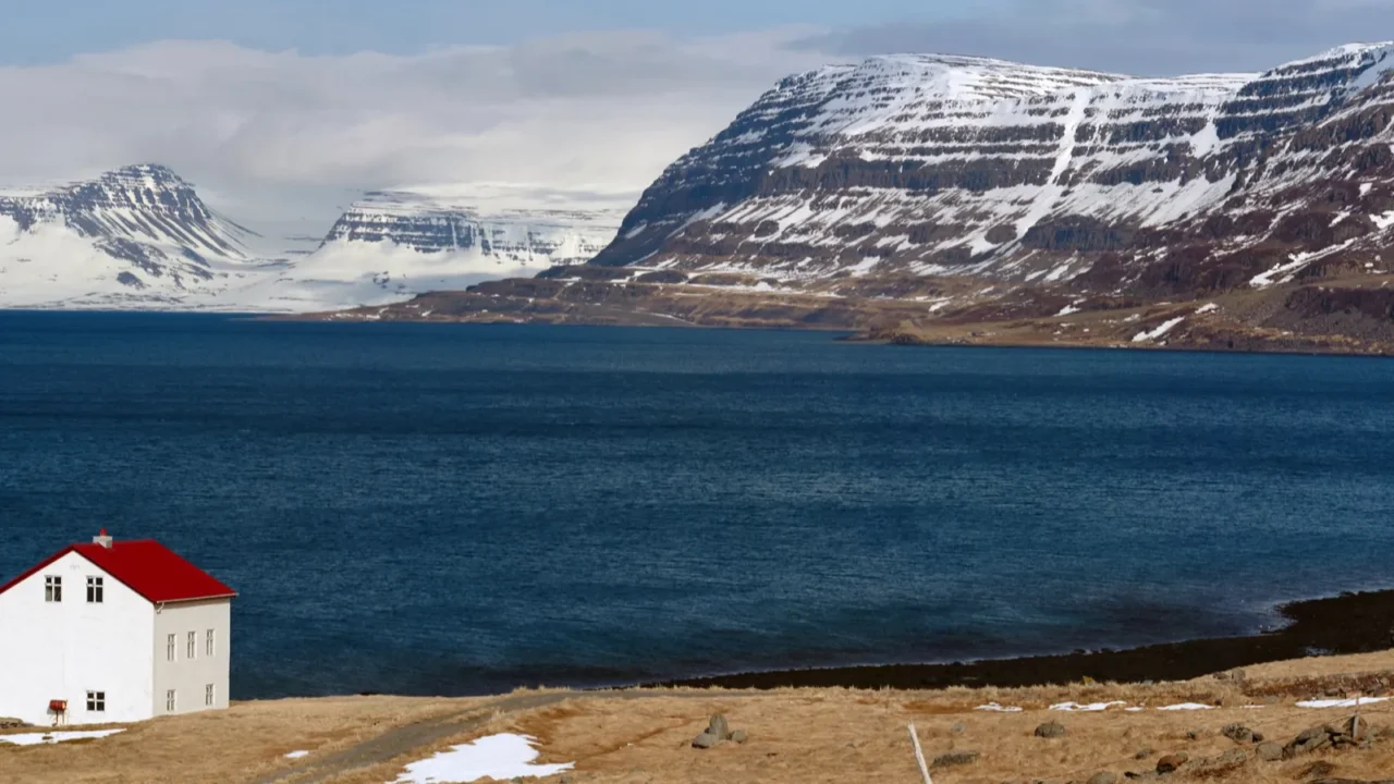 cabin near lake and snowcapped westfjords in icelandic mountains