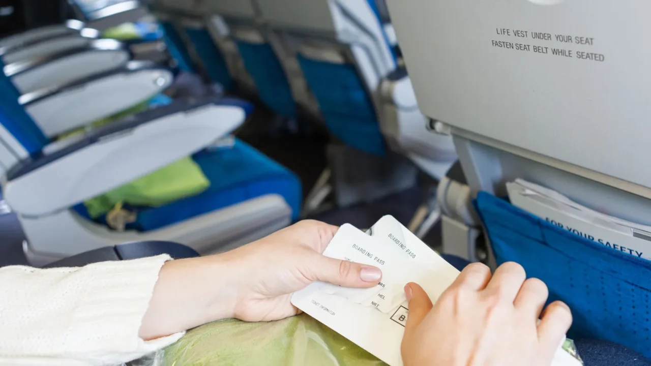 caucasian female sitting in aircraft with boarding passes in hands