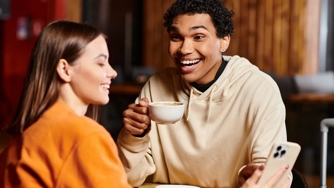 cheerful black man looking at woman sit at a wooden