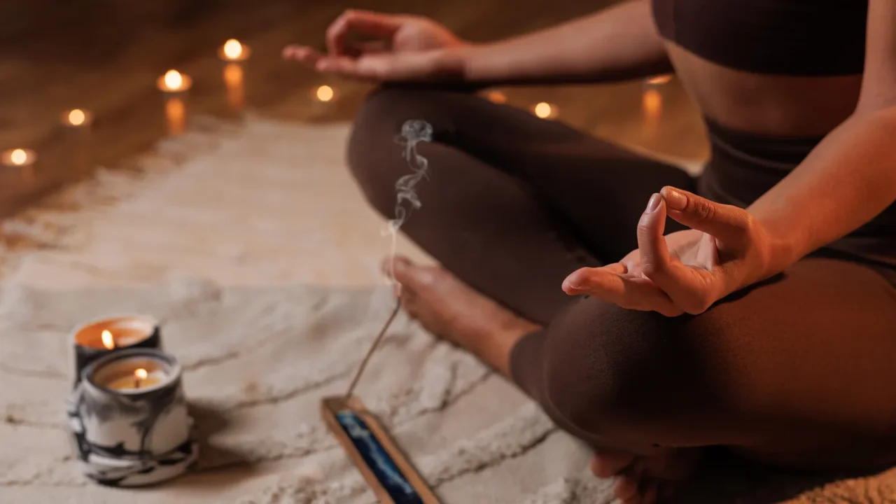 closeup of woman meditating with candles and incense creating a