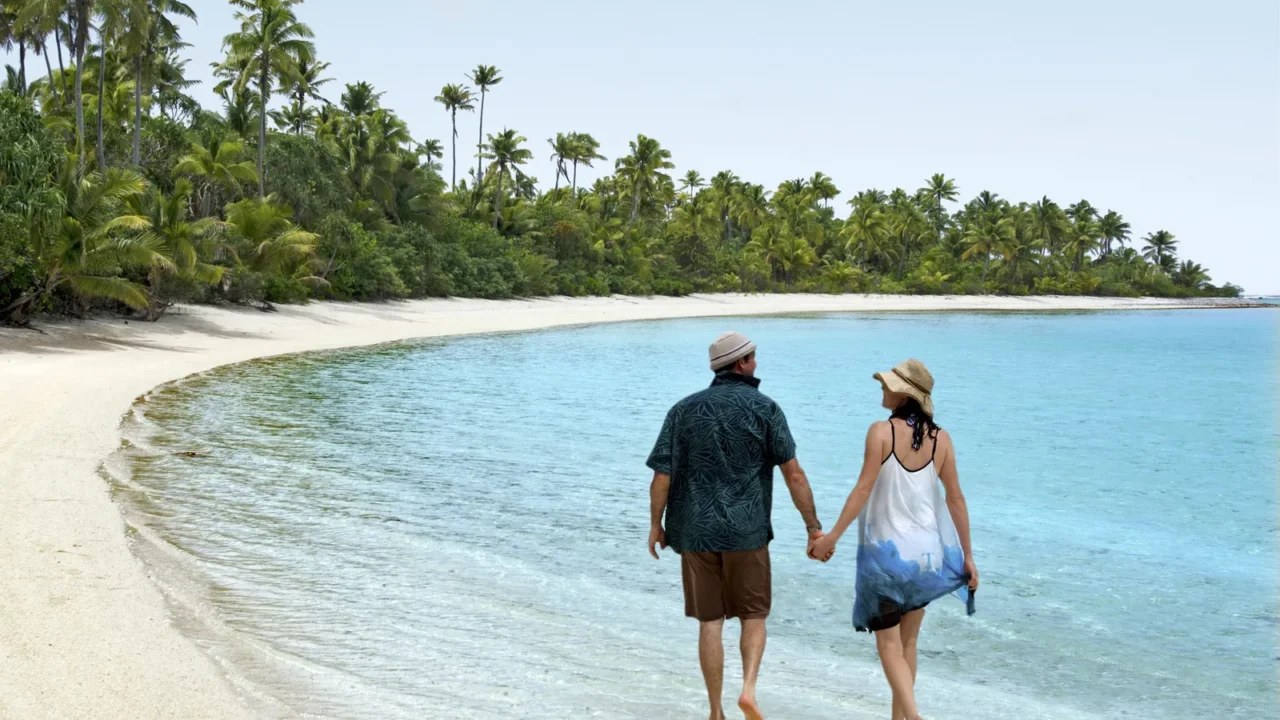 couple walk on one foot island in aitutaki lagoon cook